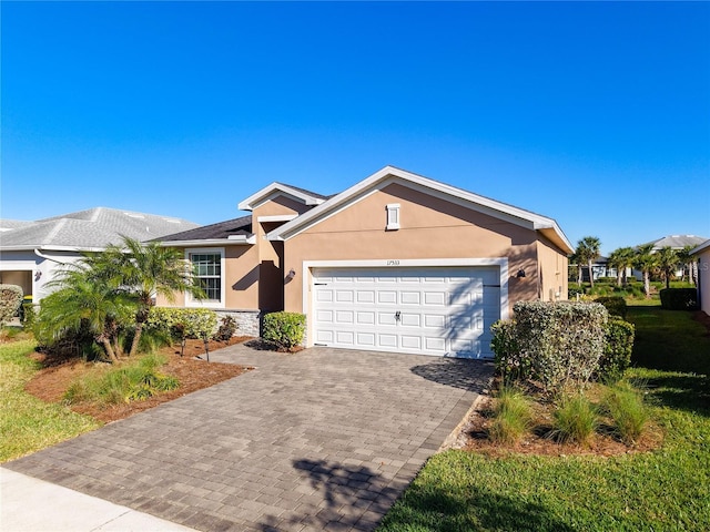 ranch-style house with stone siding, decorative driveway, stucco siding, and an attached garage
