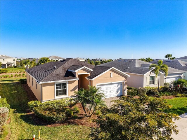 single story home featuring a front lawn, driveway, stucco siding, and an attached garage