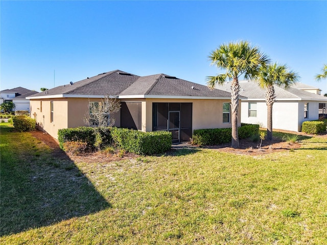 back of property with stucco siding and a yard