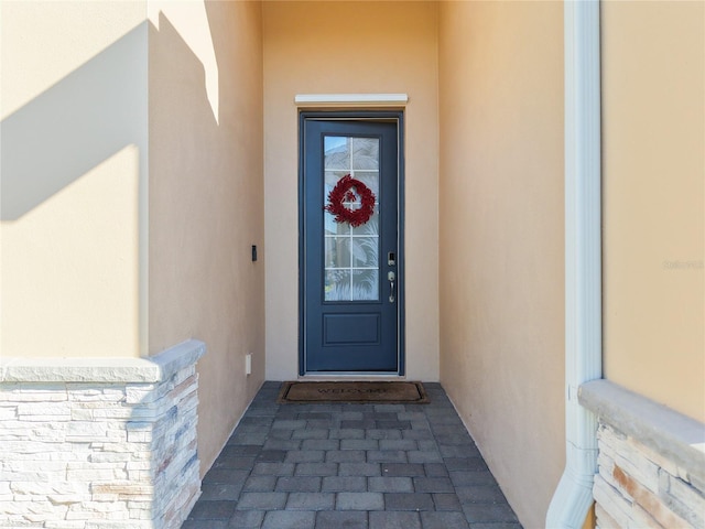 doorway to property featuring stucco siding and stone siding