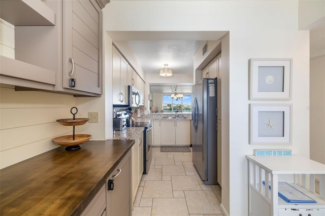 kitchen with visible vents, stone finish flooring, appliances with stainless steel finishes, a notable chandelier, and a sink