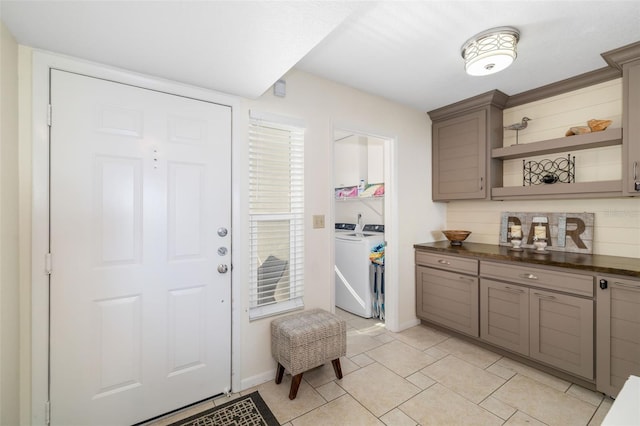 interior space with laundry area, light tile patterned floors, separate washer and dryer, and baseboards