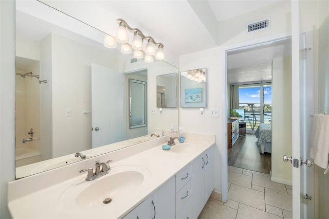 ensuite bathroom with a sink, visible vents, double vanity, and tile patterned floors