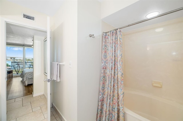 bathroom with baseboards, visible vents, expansive windows, shower / tub combo with curtain, and connected bathroom