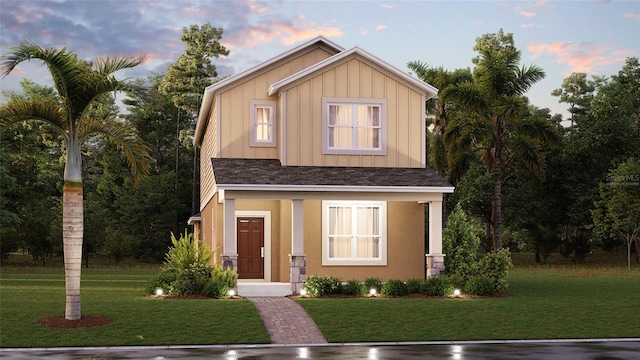 view of front of property featuring a lawn, board and batten siding, a shingled roof, and stucco siding