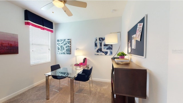 carpeted office space with a ceiling fan and baseboards