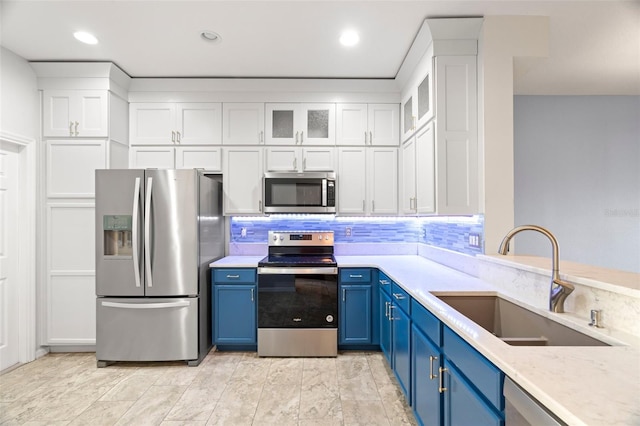 kitchen with decorative backsplash, white cabinets, stainless steel appliances, blue cabinets, and a sink