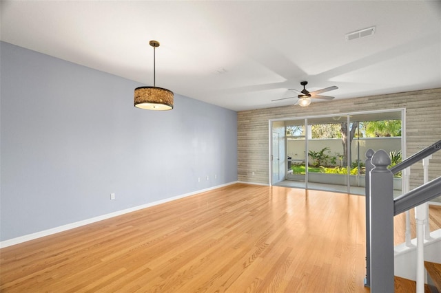 spare room featuring stairway, a ceiling fan, baseboards, visible vents, and light wood-type flooring