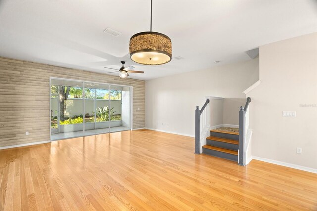 unfurnished living room featuring stairway, baseboards, light wood-style floors, and visible vents