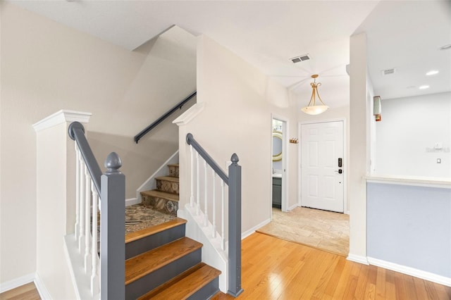 staircase featuring visible vents, baseboards, and hardwood / wood-style flooring