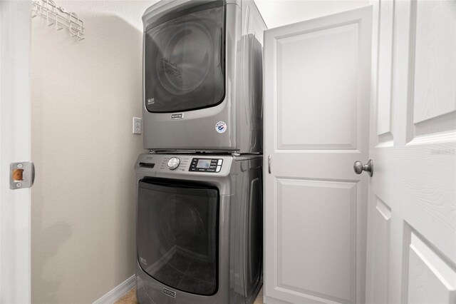 laundry room featuring laundry area, stacked washer and clothes dryer, and baseboards