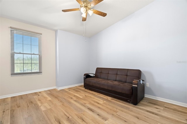 living area with a ceiling fan, lofted ceiling, wood finished floors, and baseboards