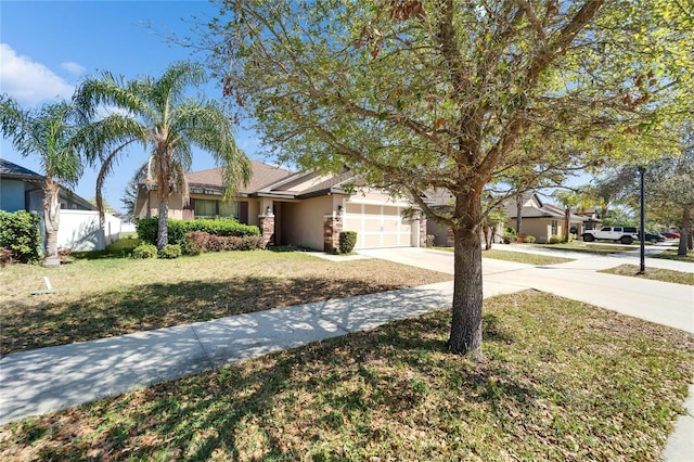 view of front facade featuring fence, driveway, an attached garage, stucco siding, and a front lawn