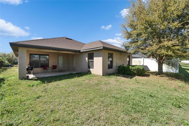 back of property featuring a patio, fence, roof with shingles, stucco siding, and a lawn