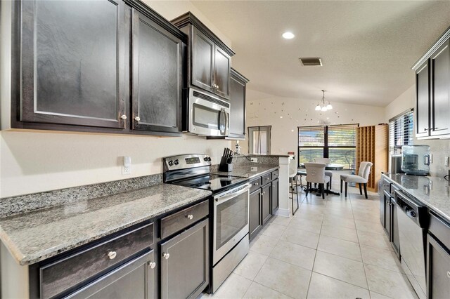 kitchen with visible vents, an inviting chandelier, appliances with stainless steel finishes, light tile patterned floors, and vaulted ceiling