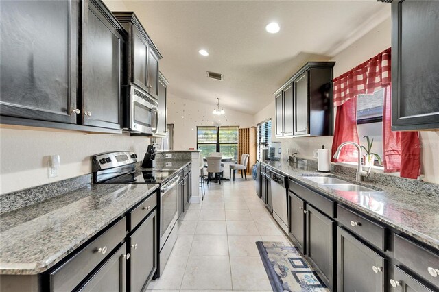 kitchen featuring light tile patterned floors, visible vents, lofted ceiling, a sink, and stainless steel appliances