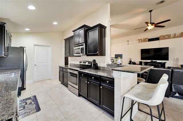 kitchen featuring visible vents, open floor plan, appliances with stainless steel finishes, a kitchen breakfast bar, and dark cabinets