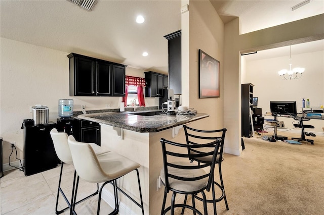 kitchen featuring tile countertops, visible vents, recessed lighting, a kitchen breakfast bar, and dark cabinets