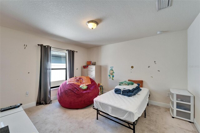 bedroom with light carpet, a textured ceiling, and baseboards