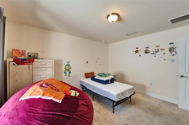 bedroom with visible vents, light colored carpet, a textured ceiling, and baseboards