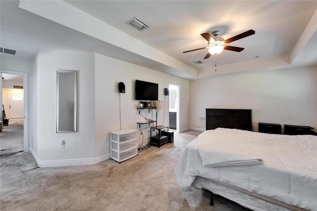 bedroom with a tray ceiling, visible vents, baseboards, and carpet