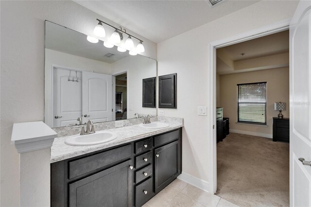 bathroom with double vanity, baseboards, and a sink