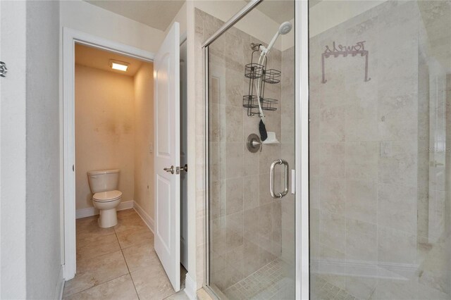 full bathroom with tile patterned flooring, a shower stall, toilet, and baseboards