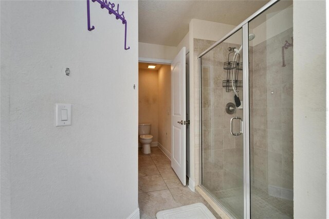 full bathroom featuring baseboards, toilet, a stall shower, and tile patterned flooring