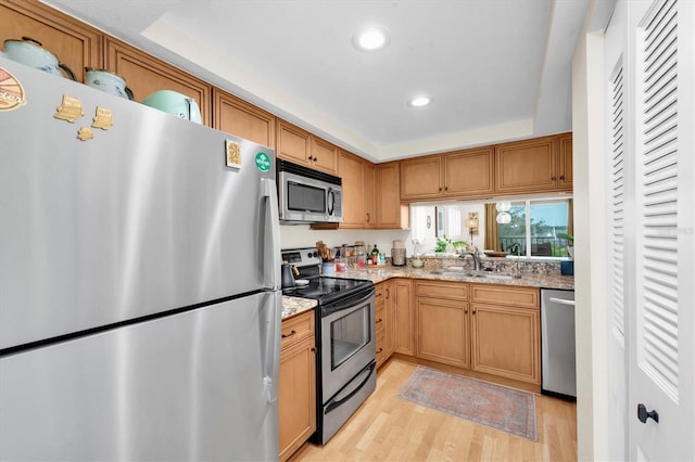 kitchen featuring a sink, recessed lighting, appliances with stainless steel finishes, light wood finished floors, and light stone countertops