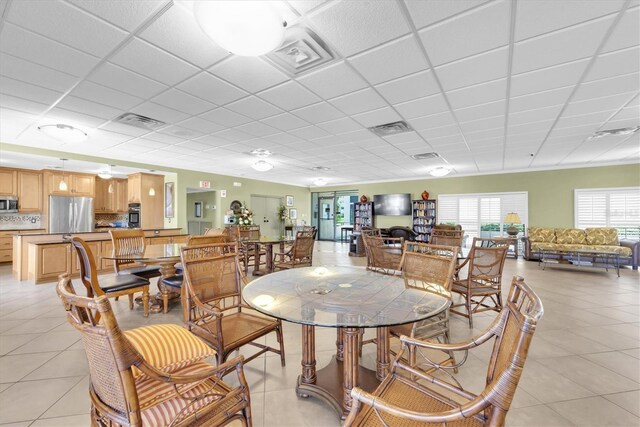 dining space featuring light tile patterned floors, visible vents, and a drop ceiling