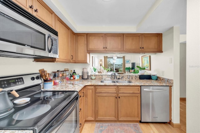 kitchen featuring a sink, light stone counters, brown cabinets, and stainless steel appliances