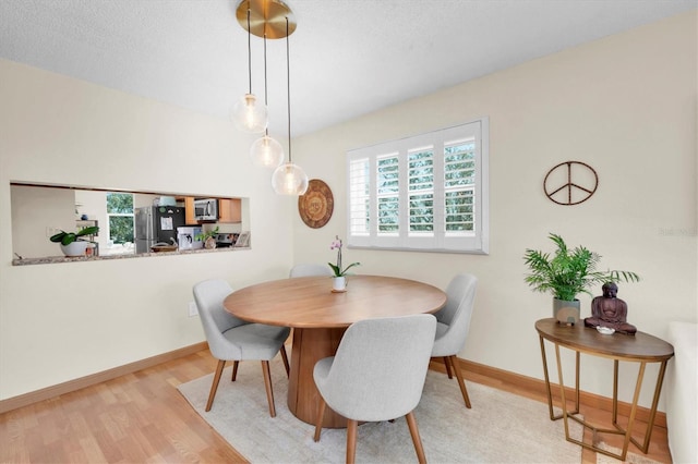 dining room with a textured ceiling, baseboards, and wood finished floors