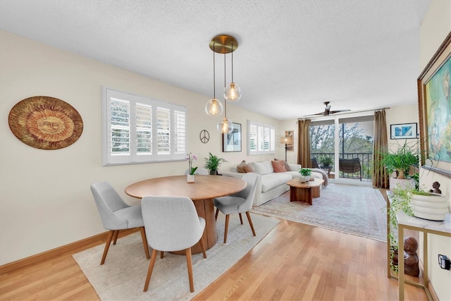 dining room with baseboards, light wood-style flooring, a textured ceiling, and a ceiling fan