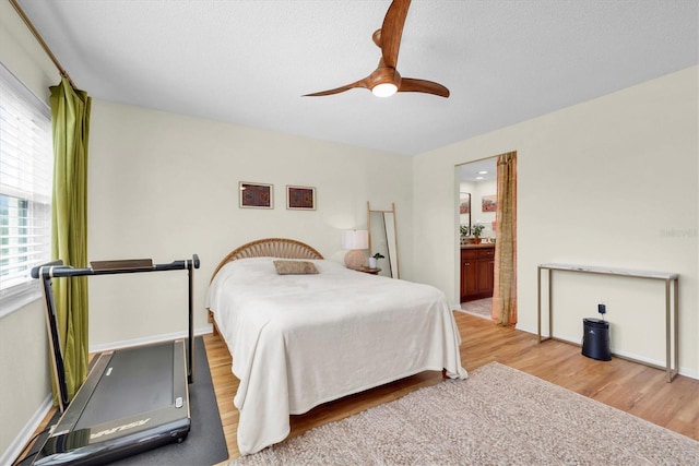 bedroom with connected bathroom, baseboards, ceiling fan, and wood finished floors