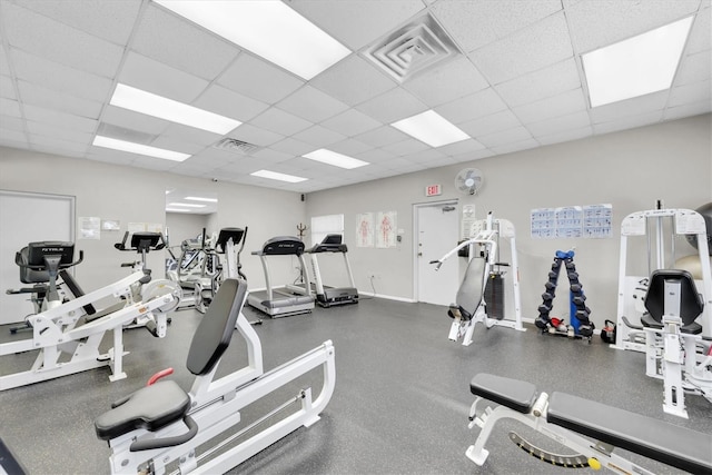 workout area with visible vents, a paneled ceiling, and baseboards