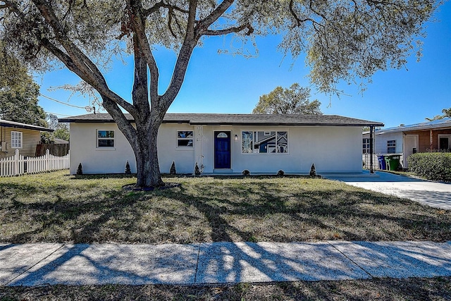 ranch-style house with stucco siding, a front yard, and fence