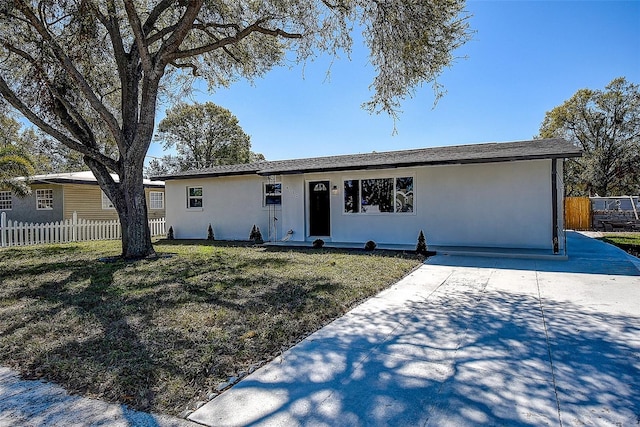 single story home featuring stucco siding, a front lawn, and fence