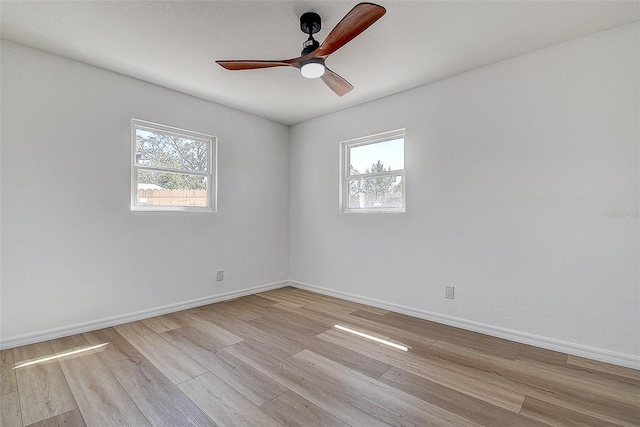 spare room with a wealth of natural light, baseboards, and light wood finished floors