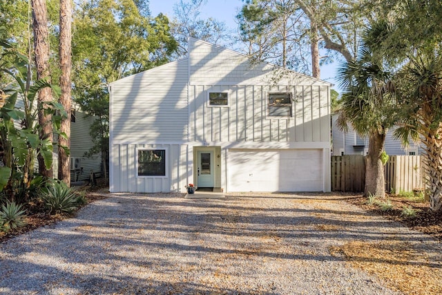 view of front of property featuring a garage, driveway, board and batten siding, and fence