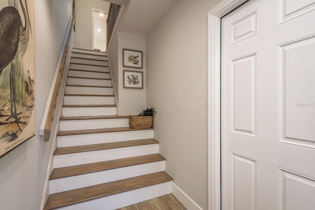 staircase featuring wood finished floors and baseboards