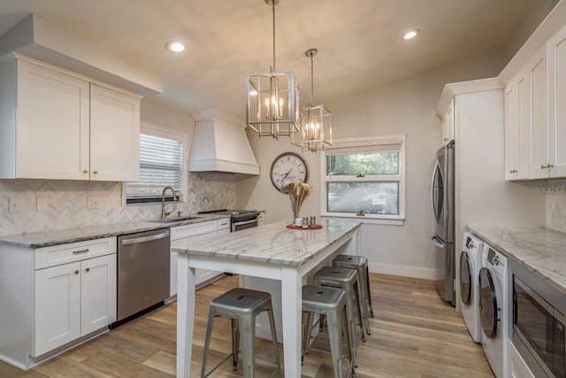 kitchen featuring light wood-type flooring, a sink, a center island, stainless steel appliances, and custom exhaust hood