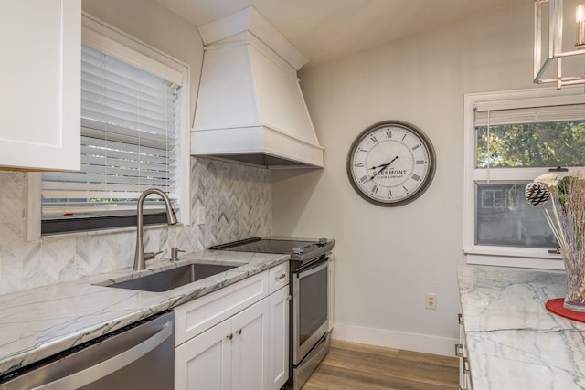 kitchen featuring white cabinets, stainless steel appliances, custom range hood, and a sink