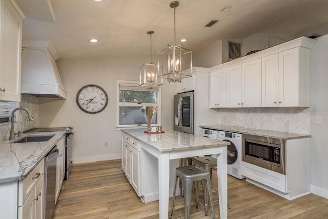 kitchen featuring backsplash, appliances with stainless steel finishes, light wood-style floors, white cabinetry, and a sink