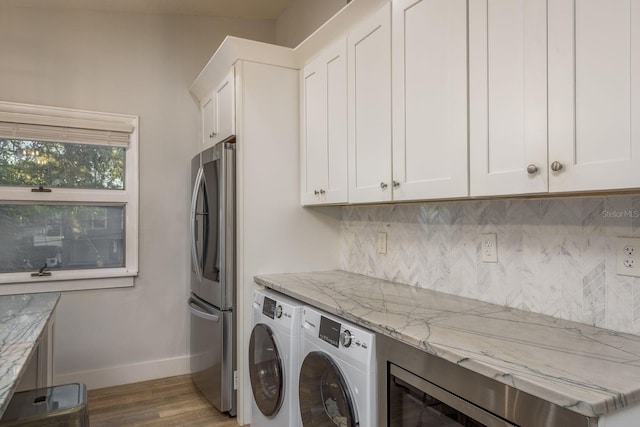 washroom featuring wood finished floors, baseboards, separate washer and dryer, and cabinet space