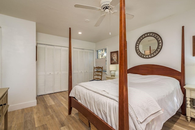 bedroom with baseboards, a ceiling fan, multiple closets, and wood finished floors