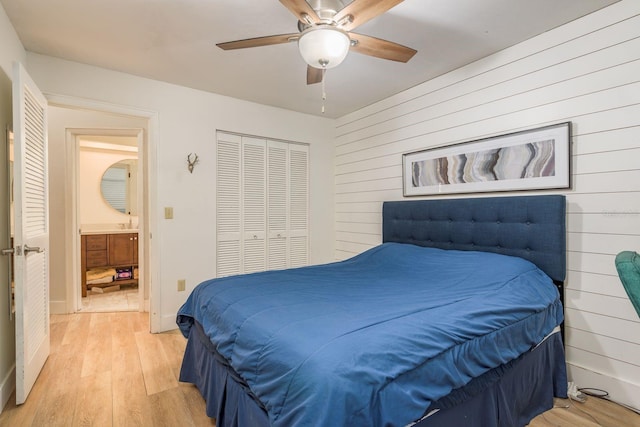 bedroom with wooden walls, baseboards, ceiling fan, light wood-style flooring, and a closet