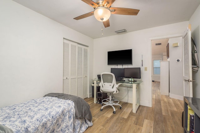 bedroom with visible vents, baseboards, ceiling fan, wood finished floors, and a closet