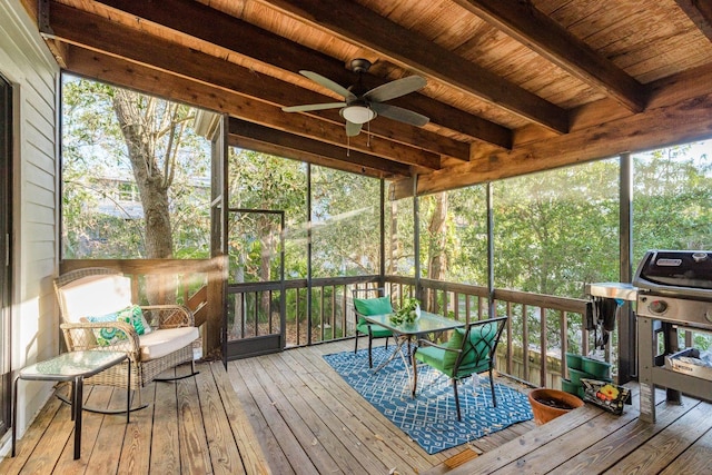 sunroom featuring beamed ceiling, wood ceiling, a wealth of natural light, and ceiling fan