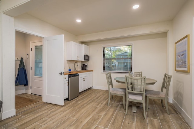 kitchen with dishwasher, white cabinetry, wood finish floors, and a sink