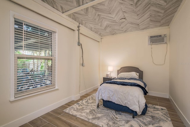 bedroom featuring wood finish floors, baseboards, and a wall mounted AC